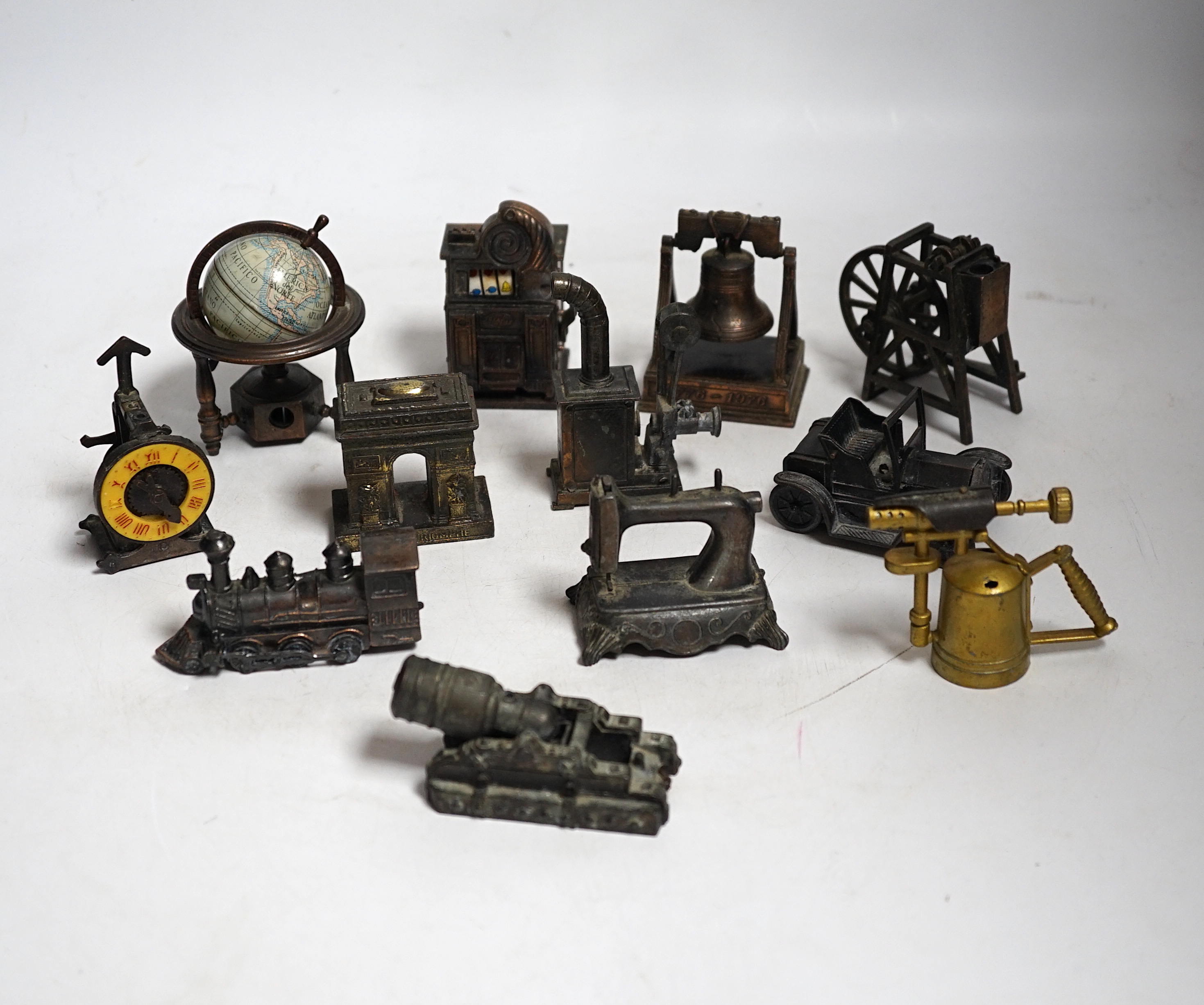 A collection of novelty metal pencil sharpeners and a pair of late Georgian silver plated candlesticks, 20cm